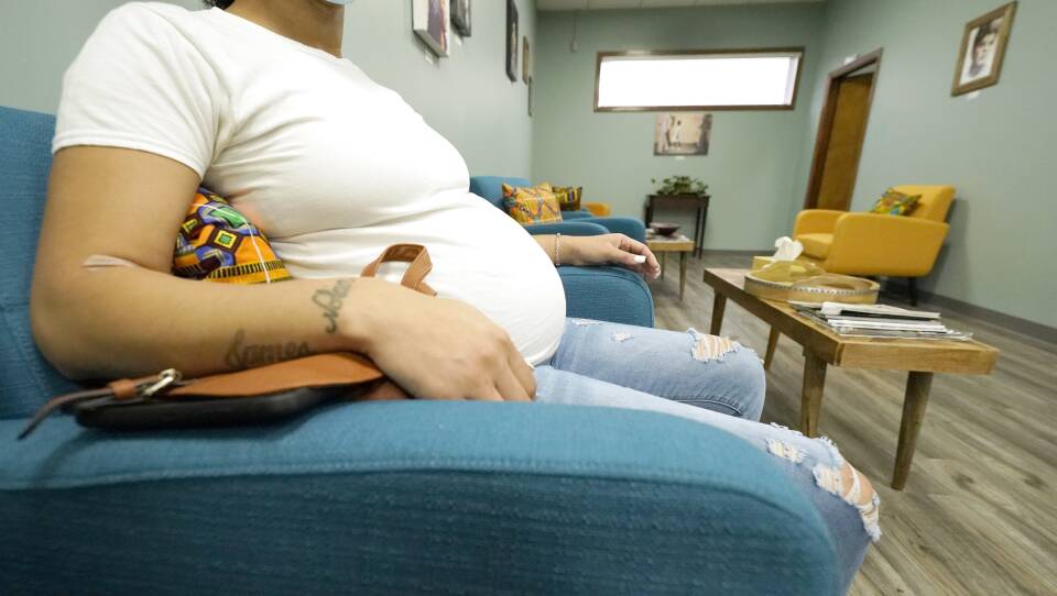 A pregnant woman sits in a waiting room.