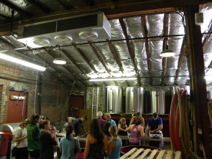 Visitors sip wine and tour the winery, watching co-op members at the sorting table.