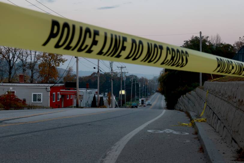 Police tape crosses a Maine road at dusk