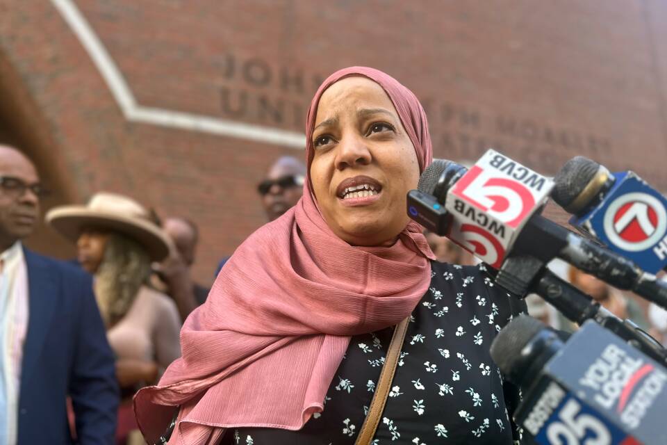 Tania Fernandes Anderson speaks outside a courthouse into reporters' microphones.