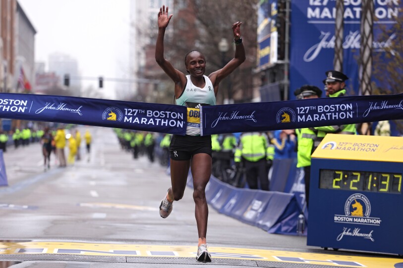 Obiri holds her hands triumphantly over her head as she breaks the tape at the finish line.