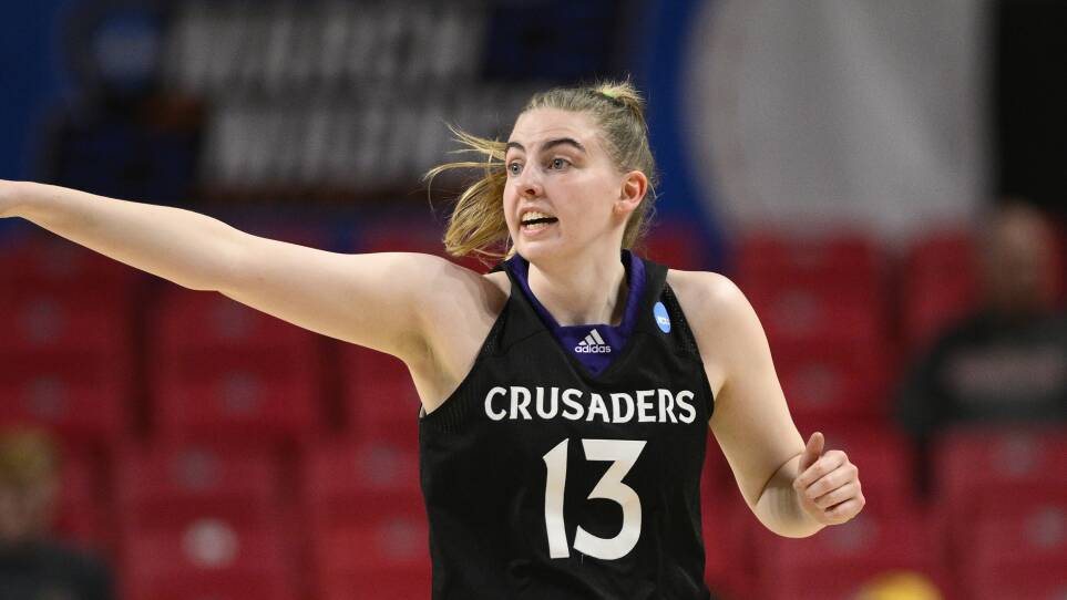 A woman in a basketball jersey with the number 13 and the word Crusaders runs on a basketball court.