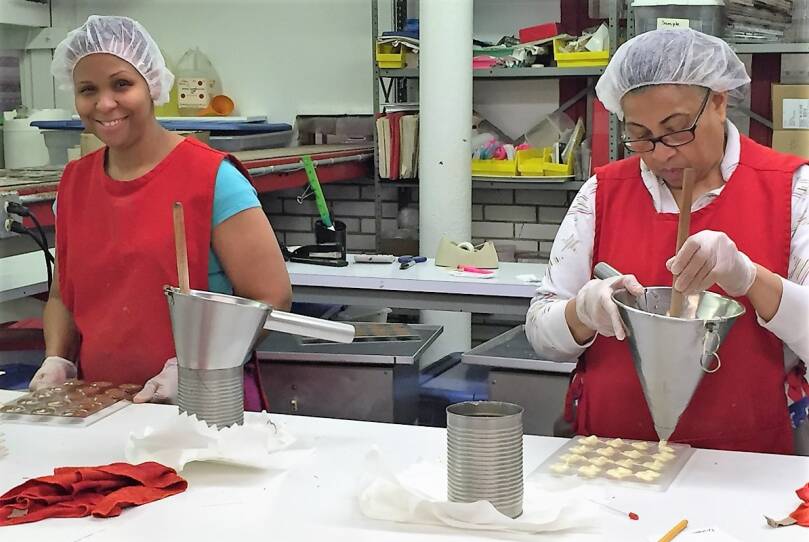 Elba Rodriguez and Dinora Perez pouring chocolate into molds.