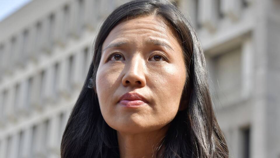 Michelle Wu looks up as she stands outside the City Hall building.