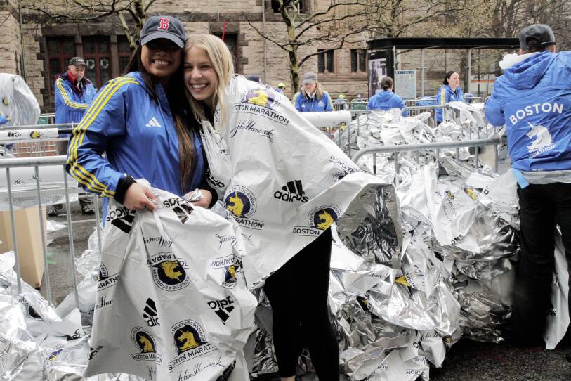 Two women stand surrounded by shiny metal blankets.