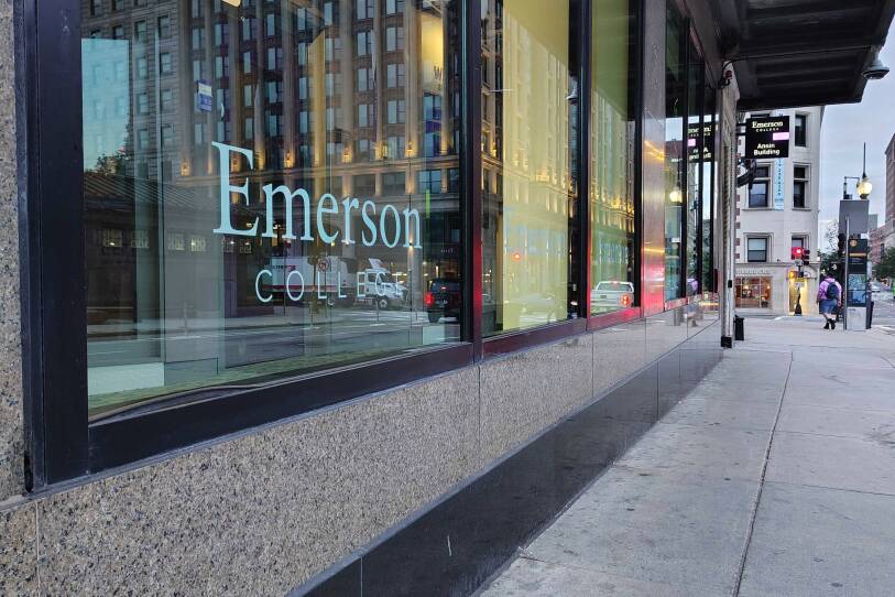 A building in a downtown business area has "Emerson College" branded on the windows.