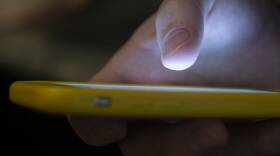 A person uses their thumb to type numbers on a smartphone.