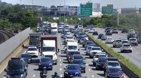 A variety of cars and trucks fill the lanes of a major highway.