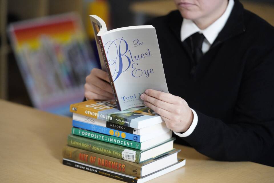 A person holds open a copy of "The Bluest Eye" as they read inside a library.