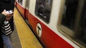 People stand on the tracks next to a Red Line train