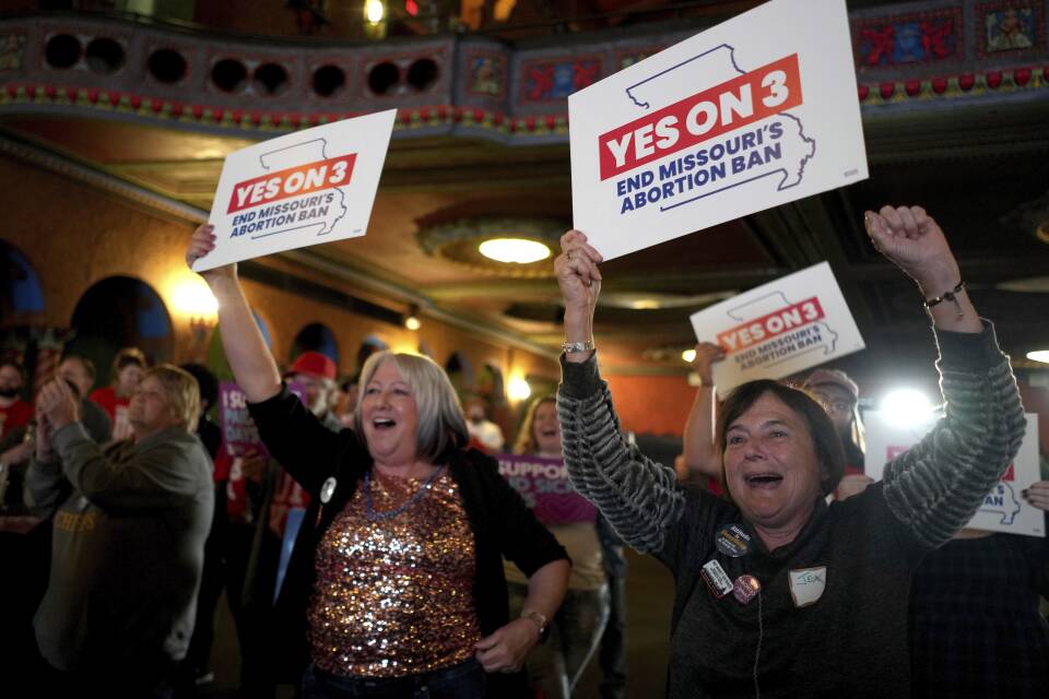 Women smiling and holding signs that read yes on 3, end Missouri's abortion ban.