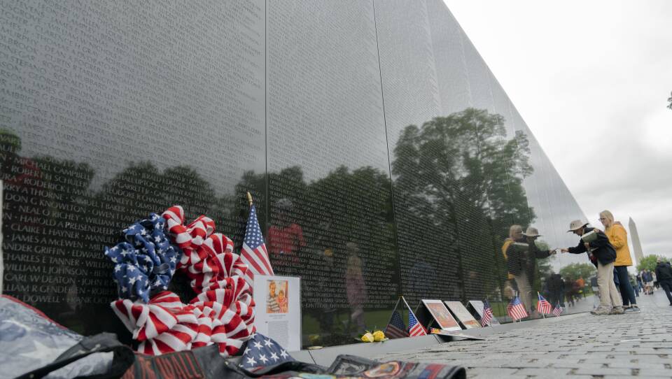 American flags and wreath next to the black vietnam Memorial in washington