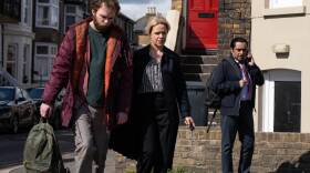 DCI Jess James (Sinéad Keenan) and DI Sunny Khan (Sanjeev Bhaskar) walk Marty Baines (Maximilian Fairley) to a squad car.