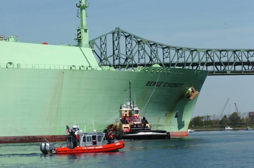 A tugboat guides a massive ship in Boston waters