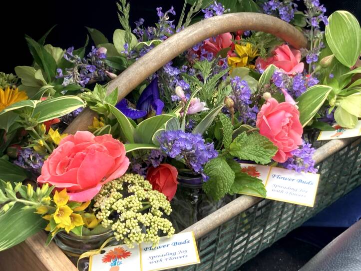 Pink, yellow and purple flowers make up small arrangements in jars.