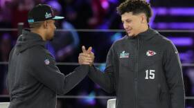 Hurts and Mahomes lock hands and smile at each other.