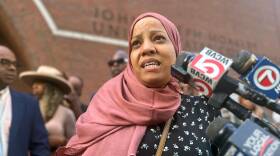Tania Fernandes Anderson speaks outside a courthouse into reporters' microphones.