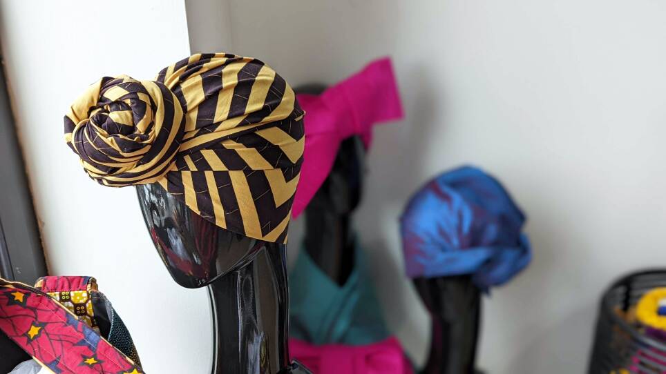 A black and yellow striped head wrap sits on a mannequin head.