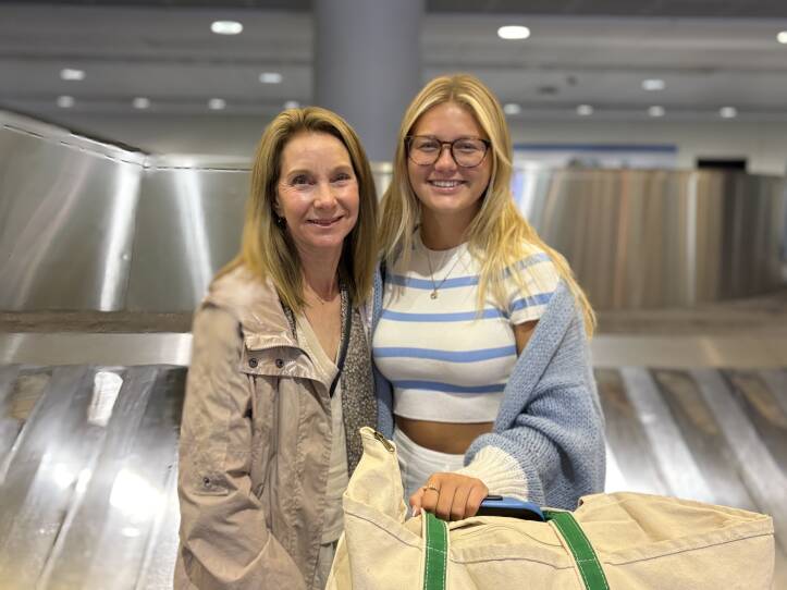 two women stand in an airport