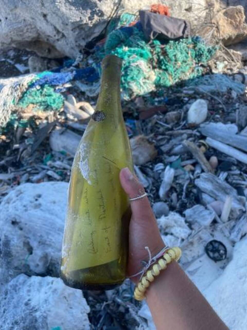 A hand holds a yellow bottle with a note inside.