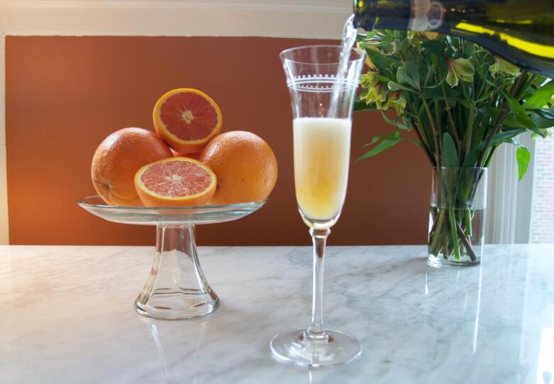 Pouring a classic mimosa with fresh oranges behind it.