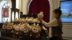 A woman arranges a display of furry brown stuffed animals.