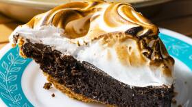 Aqua-ringed plate topped with a pie with a fudge center topped with toasted marshmallow creme