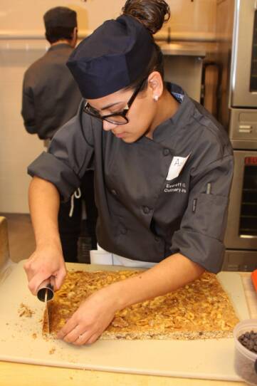 One of the future chefs cutting a pastry.