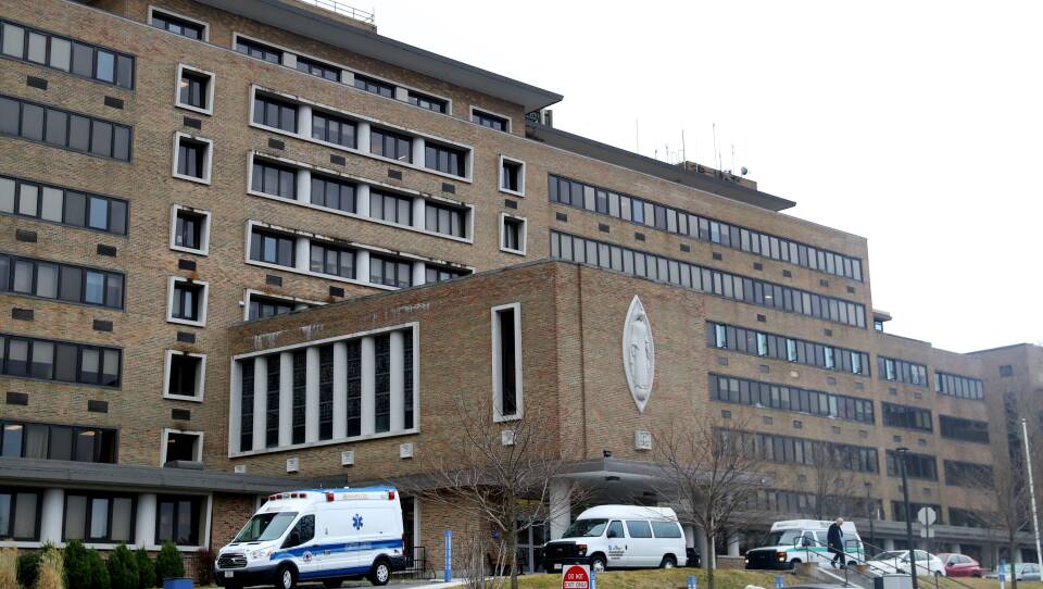 Ambulettes sit outside a large hospital.