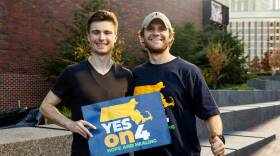 Two men stand side-by-side, holding a sign that says "Yes on 4: Hope and Healing"