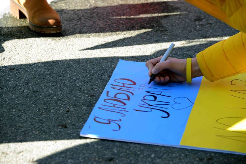 A person writes in Ukrainian  on a blue and yellow board.