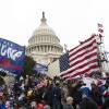 rioters photographed from the outside of the Capitol, carrying Trump 2020 and american flags