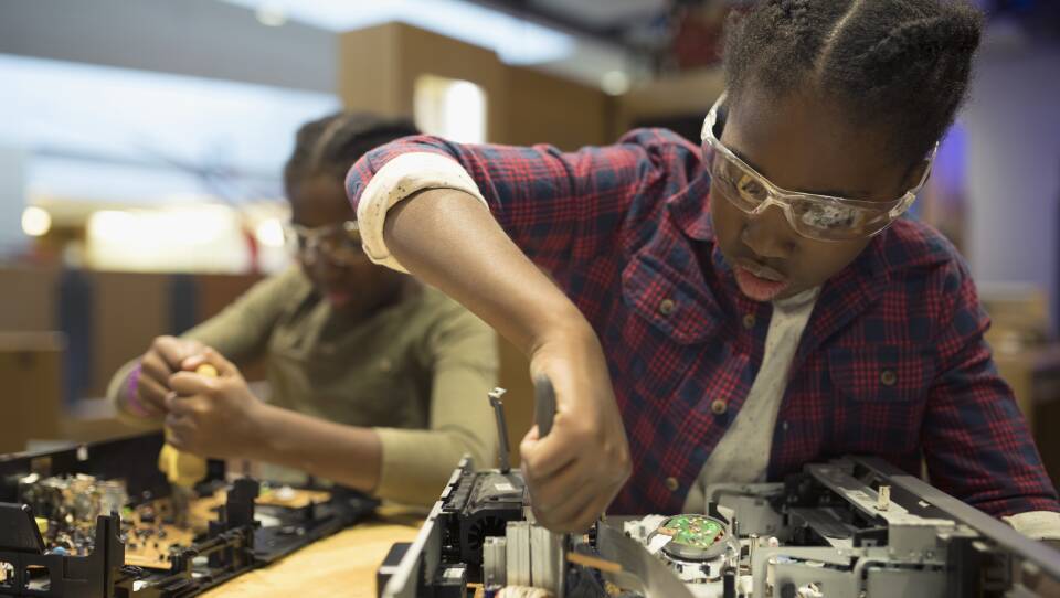 Twin sisters assembling electronics in science center workshop
