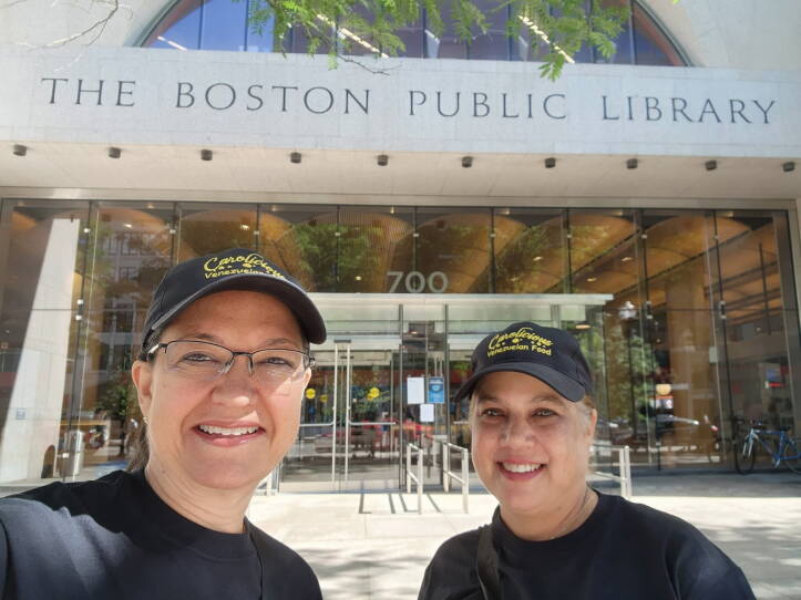Two woman wearing baseball-style hats smile at the camera.