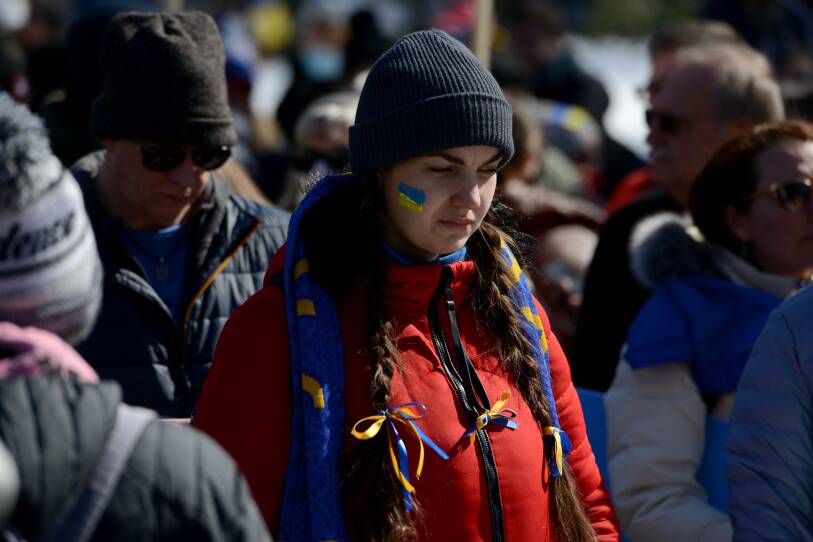 A woman in a crowd stands gazing downward.