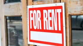 Closeup of red, white for rent sign attached, hanging on wooden apartment, house, home, building door with glass windows