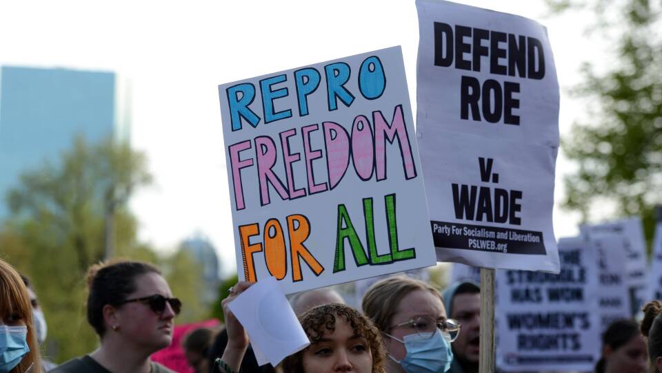 A women holds up a sign that says 'Repro Freedom For All.'