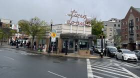 A neon sign reading "twin donuts" in cursive lettering marks the top of a tan building on a street corner.