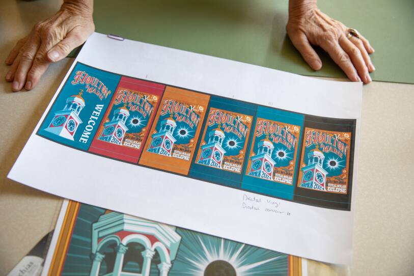 Jane Torres, director of the Greater Houlton Chamber of Commerce in Maine, considers the options on Aug. 22, 2023 for which version of the 2024 solar eclipse poster will be printed to hang around town.