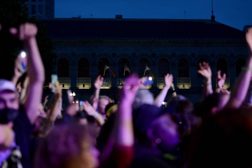 A crowd of people raise their arms in the air while dancing.
