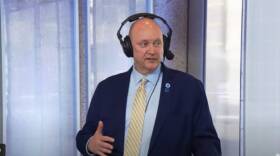 Greg Weiner wearing a radio headset and a suit