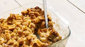 Glass baking dish filled with bread pudding with chunks of apple