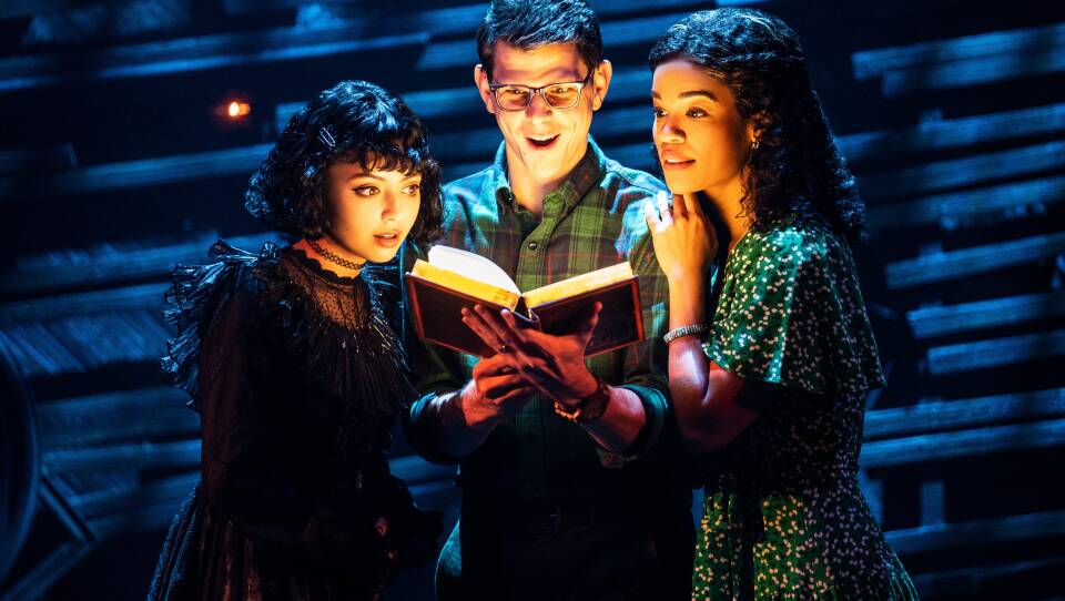 Three actors in "Beetlejuice" look at a book with a sense of wonder