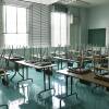 Chairs sit atop desks in an empty classroom.