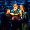 Three actors in "Beetlejuice" look at a book with a sense of wonder