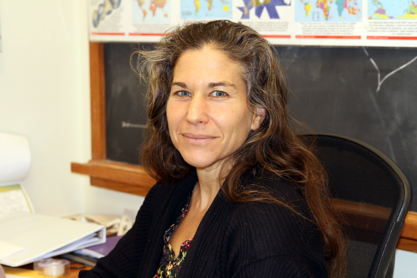 A woman in an office looks into the camera.
