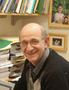 Old White Man in front of a book shelve and family photos