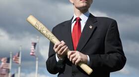 A politician holding a rolled up US Constitution
