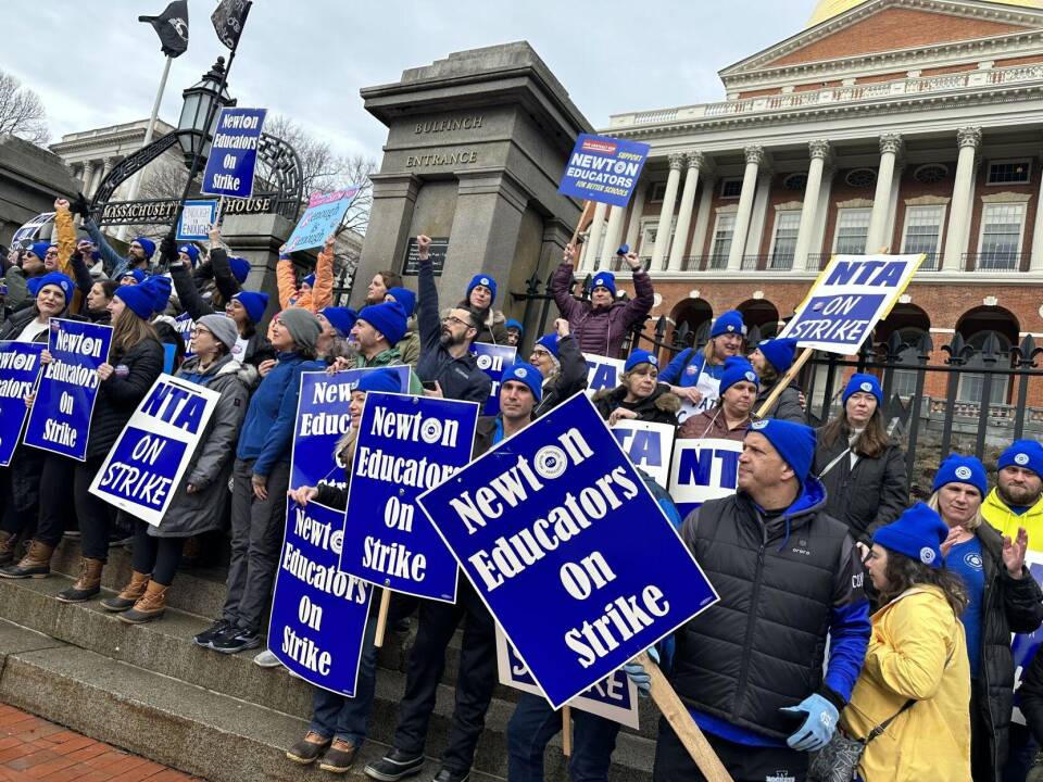 Dozens of people hold signs reading "Newton Educators on Strike" and "NTA on strike" outside the Massachusetts State House.