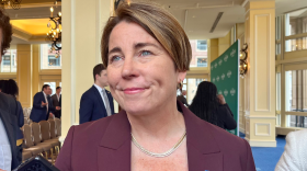 A woman with short brown hair, wearing a maroon blazer, smiles.